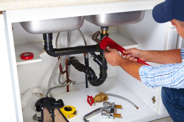 Plumber on the kitchen. Plumber with Plumbing tools on the kitchen. Renovation.
